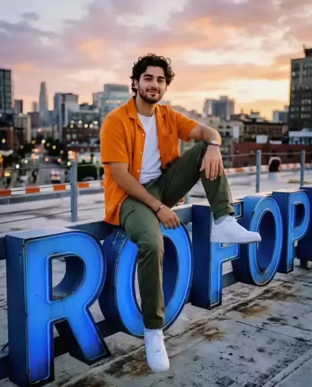Man sitting on large blue 3D letters on rooftop